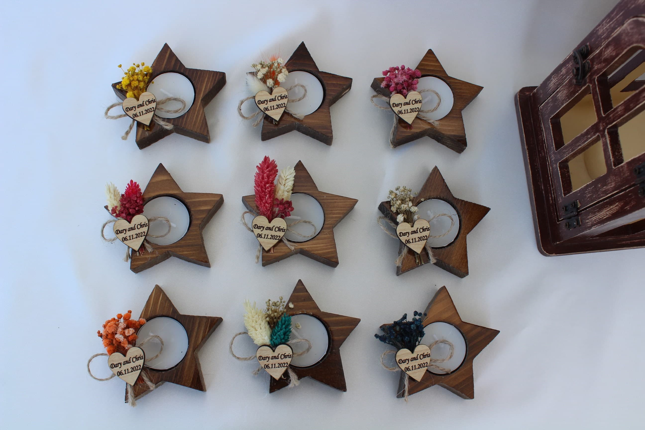 Ten star-shaped wooden tealight holders with lit tea lights, dried flower posies and personalised heart tags