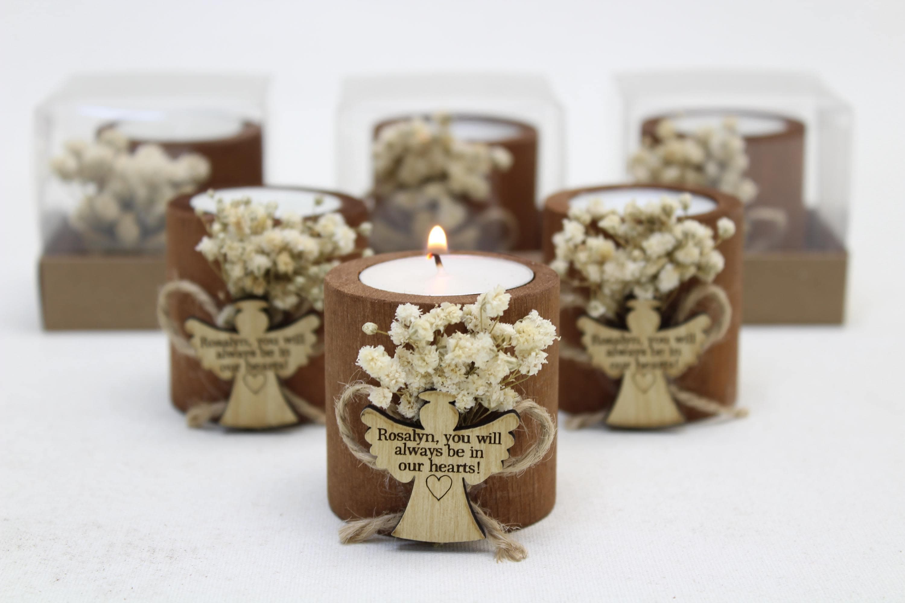 Six wooden tealight holders with white dried flowers and a wooden angel tag reading a personalised memorial message